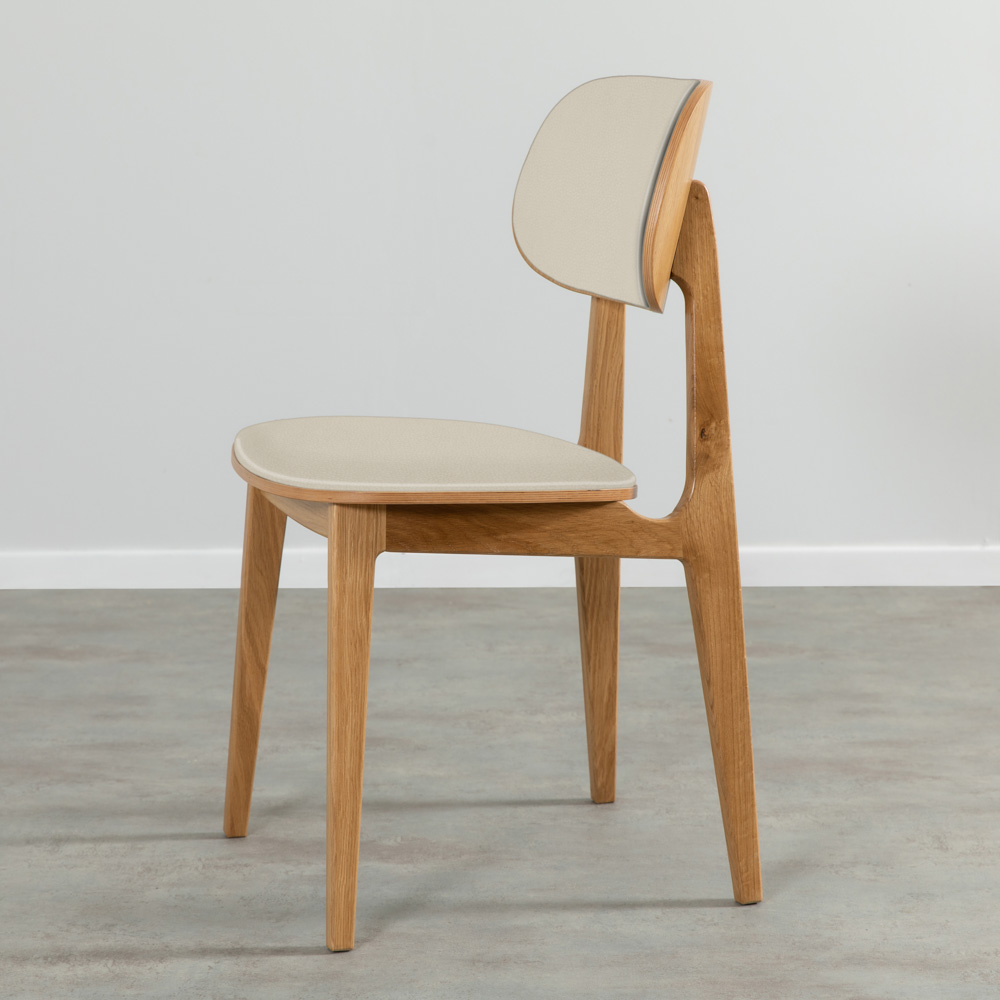 VERDA | מעוצב כיסא פינת אוכל: כיסא עץ מלא עם ריפוד בז' בהיר, מוצב על רצפה אפורה מול קיר לבן.